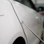 ボディパネルの合わせ目に計測棒を当てて確認している様子